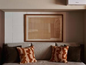 a couch with two pillows and a picture above it at illi Atra Aoyama in Tokyo