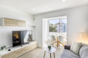 a living room with a couch and a flat screen tv at Apto Nidos cerca de la playa in L'Escala