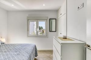 a white bedroom with a bed and a window at Apto Nidos cerca de la playa in L'Escala