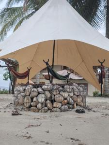 a large white umbrella and hammocks on a beach at Glampings Boreal in Mompiche