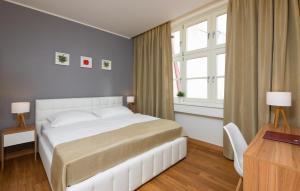 a bedroom with a white bed and a desk and window at Hotel Garden Court in Prague