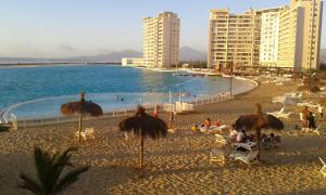 una playa con sombrillas y gente sentada en la arena en Laguna del Mar Apartamento 208, en La Serena