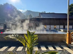 a building with smoke coming out of a pool at Bản Lướt Homestay -Ngọc Chiến Hotspring in Sơn La