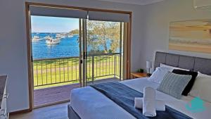 a bedroom with a bed and a large window with boats on the water at Wangi Waterfront Weekender in Wangi Wangi