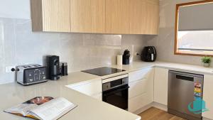 a kitchen with white cabinets and a book on the counter at Wangi Waterfront Weekender in Wangi Wangi