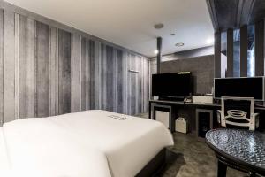 a hotel room with a white bed and a desk at Pandora Hotel in Hwaseong