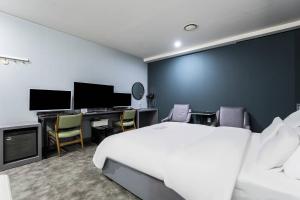 a bedroom with a bed and a desk with a computer at Pandora Hotel in Hwaseong