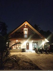 a house with a motorcycle parked in front of it at night at Surf Homestay Katiet surfing barrrels short motorcycle only minute from our places Bintang wave,Lance wave,HTs wave,monkeyWave in Katiet