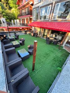 a building with a green yard with chairs and a red roof at Katson Blue Dalhousie in Dalhousie