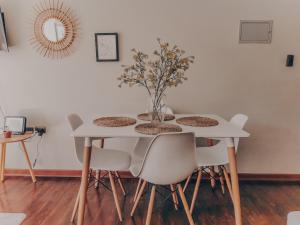 a white table with chairs and a vase on it at Hermoso Departamento Central en Concepción - hasta 4 camas - 2 Dormitorios - 1 Baño - 1 Estacionamiento - Mejor Evaluado en Chile 2023-2025 - Incluye Consola de Juegos Retro - Te ayudo con panoramas in Concepción +10 photos