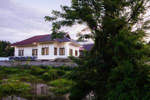a white house with a tree in front of it at Homestay Possere in Sadang