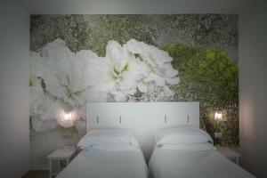 a bedroom with two beds with white flowers on the wall at Arli Hotel Hideaway Punta Ala - Adults Only in Punta Ala
