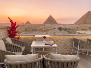 a balcony with chairs and a table with the pyramids at Rehana Pyramids View in Cairo