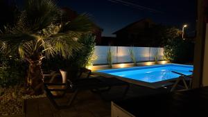 a swimming pool at night with a palm tree and lights at Luxury Apartment Lukas Pool & Parking Vodice in Vodice