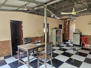 a dining room with a table and a checkered floor at Nomad Guesthouse by Buntha in Phumĭ Réach Born (2)