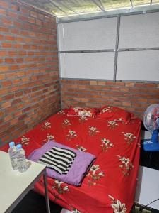 a red bed in a room with a brick wall at Nomad Guesthouse by Buntha in Phumĭ Réach Born (2)