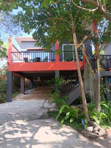 a house with a red deck next to a tree at Elevated Bungalow House 5 min from the beach 3-6 in Nathon Bay