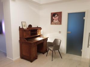 ein Klavier in einem Zimmer mit einem Stuhl und einem Gemälde in der Unterkunft Business Apartment Briller Viertel in Wuppertal