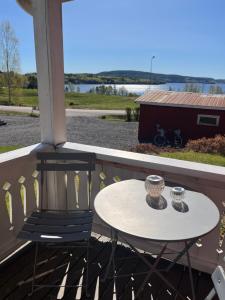a table and chairs on a porch with a view of the water at Sjönära stuga i flogned in Åmotsfors +2 photos