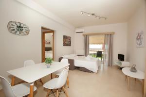 Cette chambre blanche comprend un lit, une table et des chaises. dans l'établissement Petra Thea Apartments 2, à Kalamata