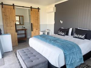 a bedroom with a large bed with a bench next to it at Guesthouse on Ostler in Twizel