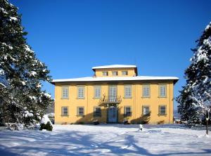 a large yellow building in the snow with trees at Villa I Delfini in Vicchio