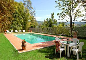 a swimming pool with a table and chairs next to it at Villa I Delfini in Vicchio