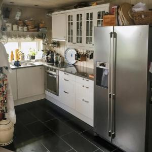 a kitchen with white cabinets and a stainless steel refrigerator at Cozy Cabin With Økstrafjord View in Jelsa