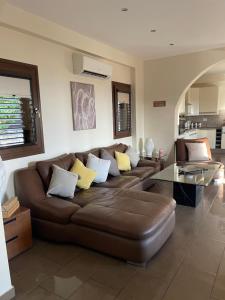 a living room with a brown couch and a table at Villa Balmoral in Peyia