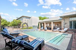 a swimming pool with chaise lounges and chairs around it at King Aqua Suite Walkable Legacy West King Bed, Pool & Gym in Plano