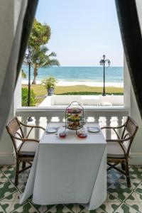 a white table with chairs and a view of the beach at Cape Panwa Hotel Phuket in Panwa Beach