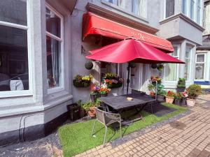 a table with a red umbrella in front of a building at The Aberford in Blackpool