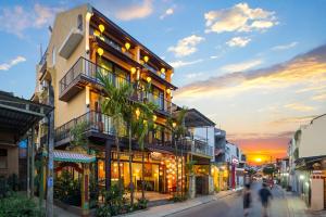 a building with people walking down a street at sunset at Solea Boutique Hoi An - Grand Opening April 2026 in Hoi An