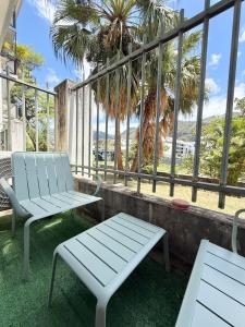 two chairs and a bench on a balcony with palm trees at Le Tiny Studio in Saint-Denis