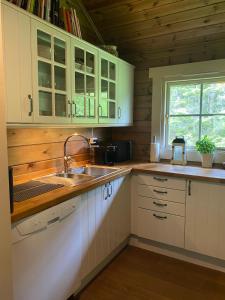 a kitchen with white cabinets and a sink and a window at Cozy log cabin in Geiranger in Geiranger