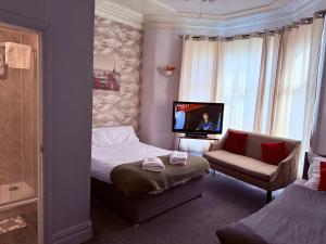 a bedroom with a bed and a tv and a chair at The Aberford in Blackpool