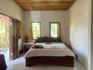 a bedroom with a large bed in a room with windows at Kembang Kuning Cottages in Tetebatu