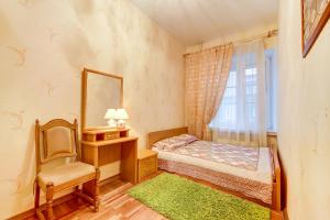 een slaapkamer met een bed, een stoel en een spiegel bij Apartment on Nevsky 13 in Sint-Petersburg