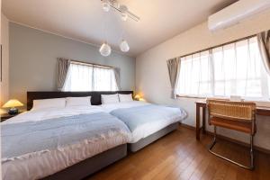 a bedroom with a large bed and two windows at Ninifuni Kanazawa in Kanazawa