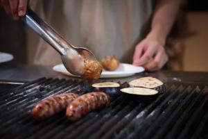 a man cooking sausages and other foods on a grill at Ski Rider Hotel in Kalkite