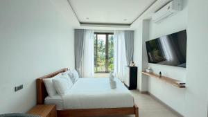 a white bedroom with a bed and a window at Sunrio Beach Hotel Sichon in Ban Plai Thon