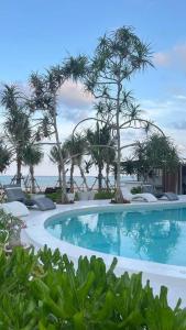 a swimming pool with palm trees and the ocean at Sunrio Beach Hotel Sichon in Ban Plai Thon