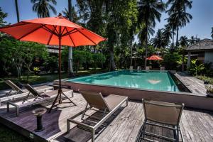 a deck with chairs and an umbrella and a pool at CocoCool Villas in Hinkong