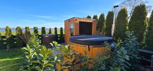 a wooden toilet in a garden with two trash cans at Mielnova Adults Only Jacuzzi & Sauna Apartamenty in Mielno