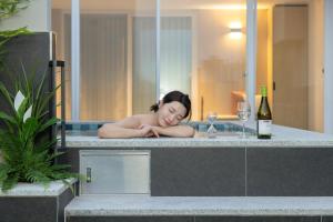 a woman laying in a bath tub with a bottle of wine at Daejeon Anook Hotel Yuseong Oncheon Station in Daejeon