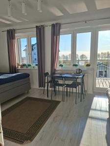 a living room with a table and chairs and windows at Azalia 32 Mielno l in Mielno