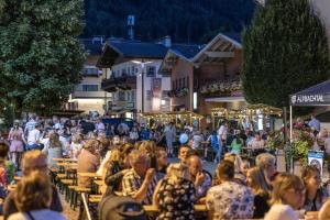 a crowd of people sitting at tables in a street at Haus Sonnblick Chalet in Reith im Alpbachtal