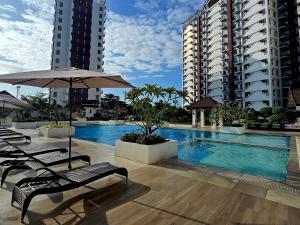 a pool with chairs and an umbrella and two tall buildings at Kai's Luxe Balcony Suite at Royal Oceancrest Mactan in Mactan Island