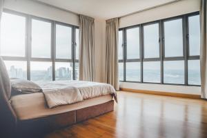 a bedroom with large windows and a bed with a wooden floor at Teega Residence near Puteri Harbour Iskandar Puteri by Our Stay in Nusajaya +223 photos