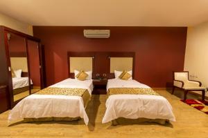 a hotel room with two beds and a chair at رؤوم إن للشقق الفندقية-سكاكا in Sakakah +40 photos